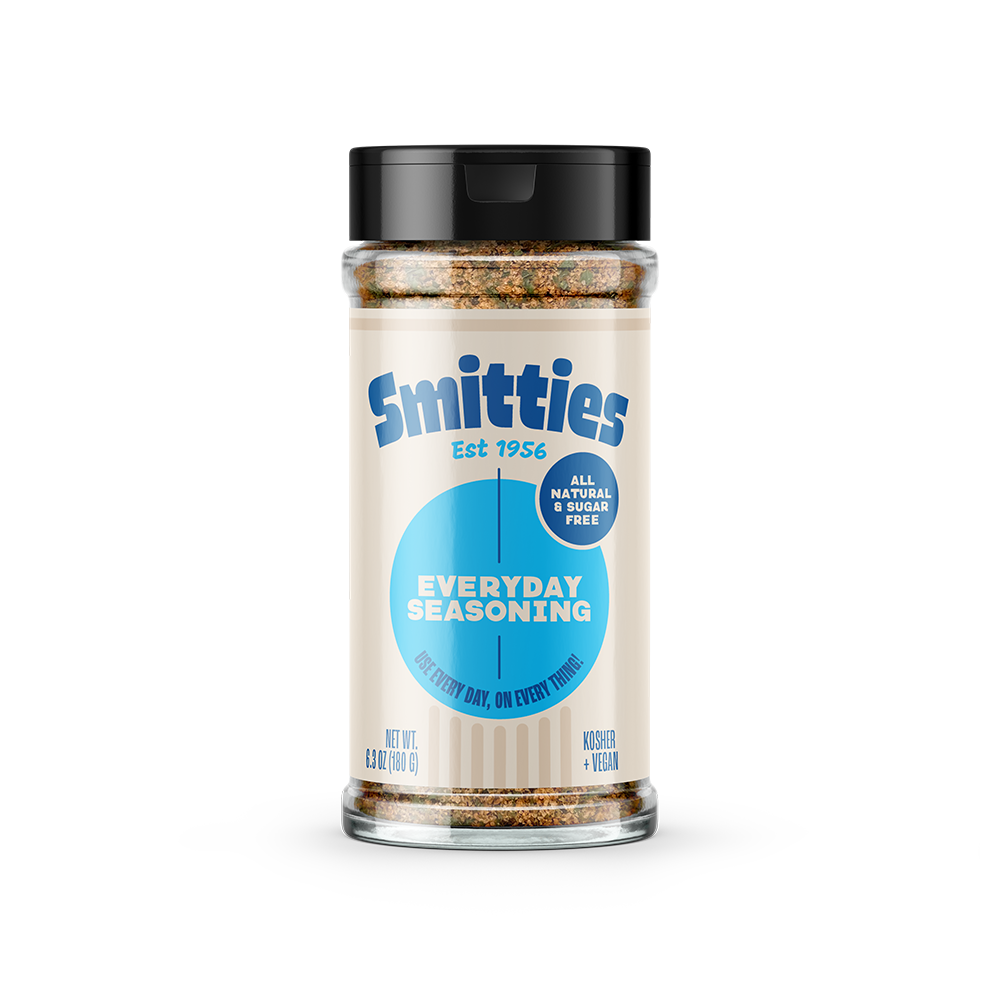 A 6.3oz shaker of Smitties Everyday Seasoning. The label features the company logo on a cream background, with a light blue circle containing the subheading “Everyday Seasoning” in block letters. Under the subheading, text reads “Use every day, on every thing!” The label also contains the claims “all natural & sugar free;” kosher; and vegan.