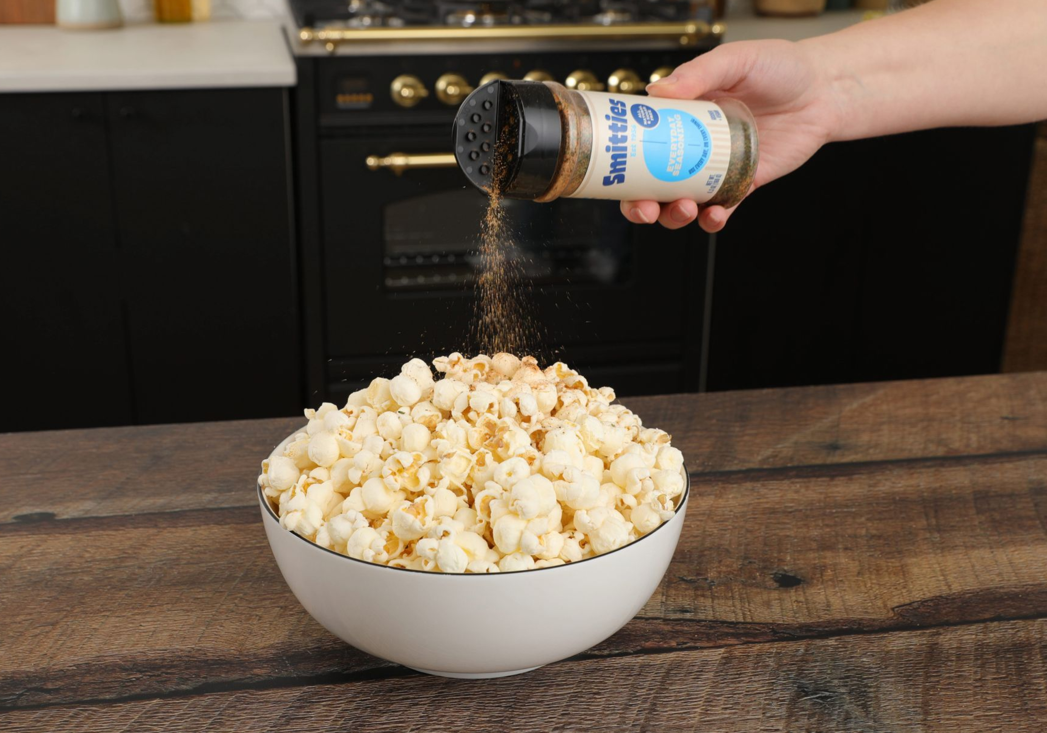 Shaking Smitties over a bowl of popcorn